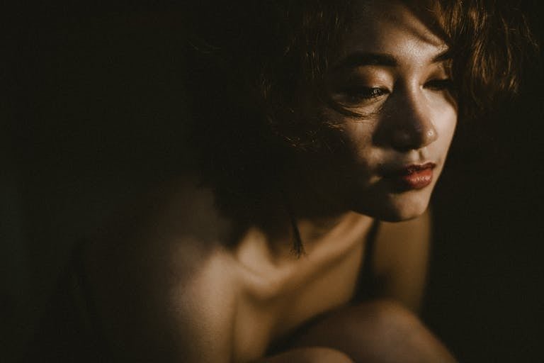 Moody portrait of a woman in soft lighting, conveying deep emotion.